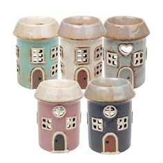 four ceramic houses with hearts on them are shown in different colors and sizes, one has a heart at the top