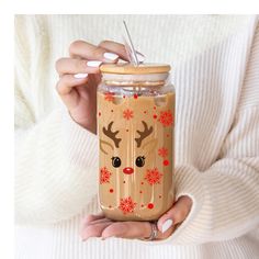 a woman holding a cup with a straw in it and reindeer face on the lid