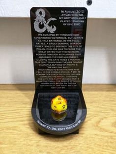 a yellow and black dice sitting on top of a wooden table next to a plaque