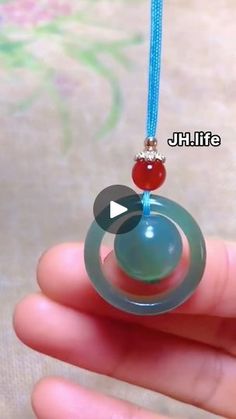 a hand holding a glass ball with a bead on it's end and a blue cord