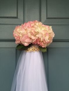 a bridal gown with pink and white flowers on the headpiece, against a green door