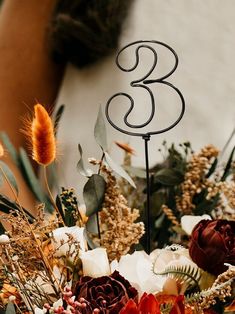 there is a wedding cake with a number on it and flowers in the foreground