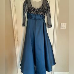 a blue dress hanging on a door with a black lace top and sleeves over it