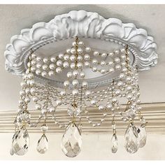 a chandelier hanging from the ceiling with pearls and crystal drops on it's sides