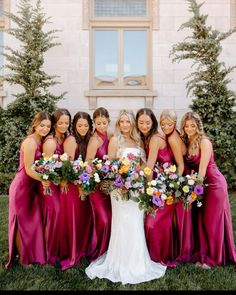 a group of women standing next to each other in front of a building with flowers