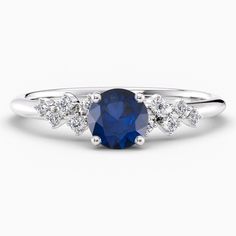 a blue sapphire and diamond ring with three diamonds on the band, set in white gold