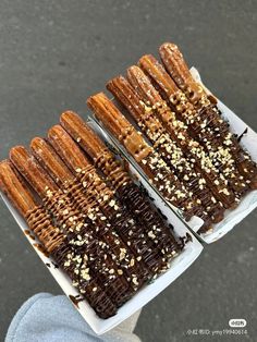 three trays filled with chocolate covered donuts and sprinkled with sesame seeds