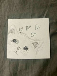 a drawing of a cat's face with hearts drawn on the paper next to it