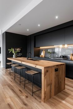 an open kitchen and dining area with wood flooring, black cabinetry and white walls