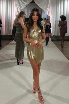 a woman walking down a runway in a gold dress