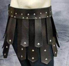 a mannequin wearing leather armor with metal rivets and spikes on it