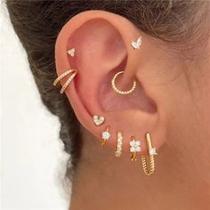 a woman wearing three different ear piercings on her left ear and one with an arrow