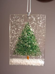 a glass christmas tree ornament hanging on a wall