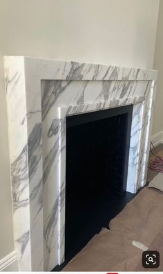 a fireplace with white marble surround and black mantel in the middle of a room