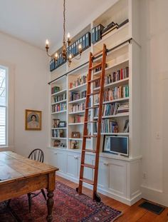 a ladder leaning up against a bookshelf next to a table and chair in a room