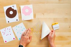 someone is cutting out paper with scissors on a wooden table next to doughnuts