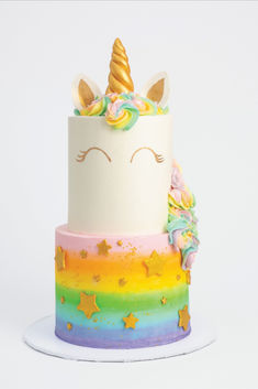 a multi - colored cake with a unicorn's face on top and stars around it