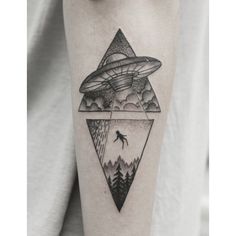 a man's arm with an alien flying over the mountains and trees on it