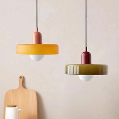 three different colored lights hanging from the ceiling next to a cutting board and utensil