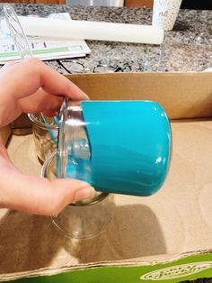 a person is pouring something into a glass in a box on the counter with other items