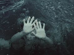 two hands reaching out from the water to touch each other's palms in black and white