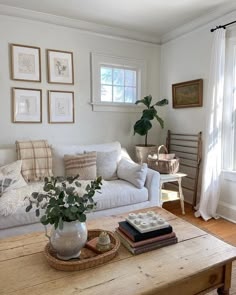 a living room with white couches and pictures on the wall above it's coffee table