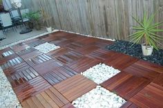 a wooden deck with rocks and gravel in the center, next to a small potted plant