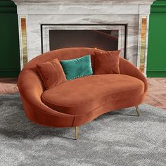 an orange couch sitting on top of a rug in front of a fire place with green walls