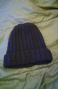 a purple knitted hat laying on top of a bed