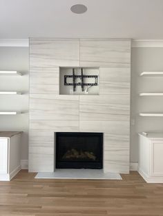 an empty living room with a fireplace and shelves