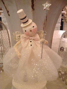 a snowman with a top hat and cane in a white tulle dress on display