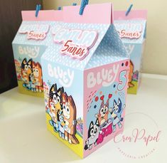 two boxes with cartoon characters on them are sitting on a white counter top, one has blue handles and the other is pink