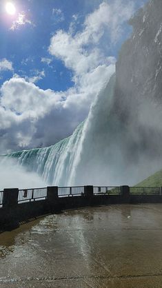 a large waterfall is shown with the sun in the sky above it and water below