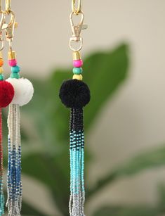 two tasseled earrings hanging from chains on a plant