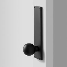 a black door handle on the side of a white wall next to a light bulb