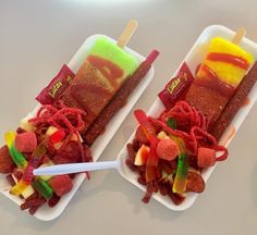 two plastic trays filled with different types of fruit and ice cream popsicles on top of each other