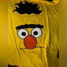 the face of an angry bird on a yellow shirt with black hair and red nose