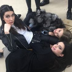 two women are laying on the ground with their legs crossed and one is wearing a black jacket