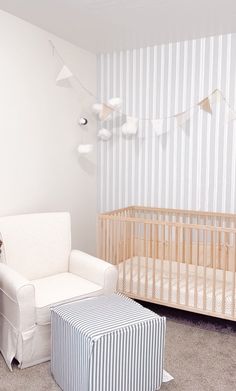 a baby's room with a crib, chair and ottoman