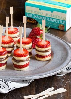 mini cheesecakes with strawberries are arranged on a silver platter next to a box of buttermilk pancakes