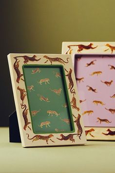 two small wooden frames with cats on them, one is pink and the other is green