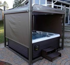 a hot tub sitting on top of a brick patio next to a covered area with steps