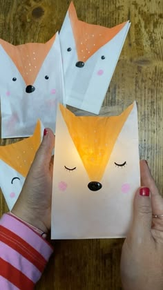 three paper foxes with their eyes closed and one being held up by someone's hand