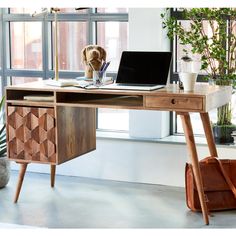 a wooden desk with a laptop on it next to a potted plant and window