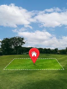 a red marker with a house on it in the middle of a green field under a blue sky