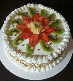 a white cake topped with sliced kiwi and strawberries