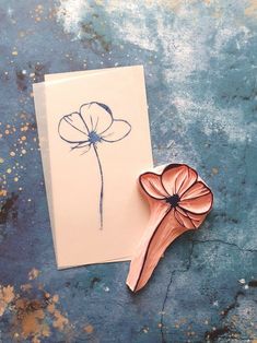 a piece of paper with a flower on it next to a card that has been drawn