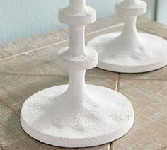 two white candlesticks sitting on top of a wooden table