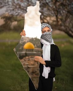 a woman holding up a piece of paper with an image of a mosque in the background