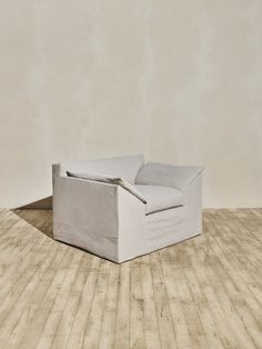 a white couch sitting on top of a hard wood floor next to a beige wall